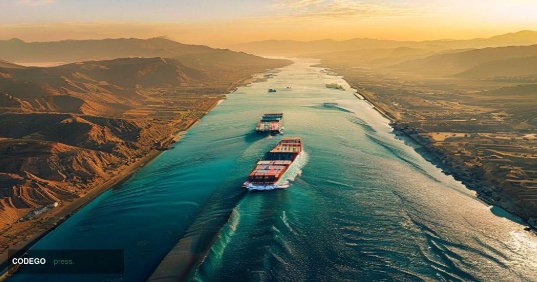 A dramatic aerial view of the Strait of Hormuz waterway at golden hour, showing the narrow channel between Iran's mountainous