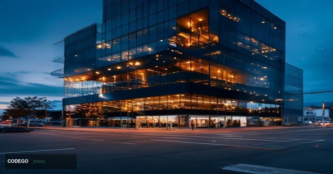 A dramatic photorealistic editorial photograph showing a modern glass office building at dusk with darkened windows and a few