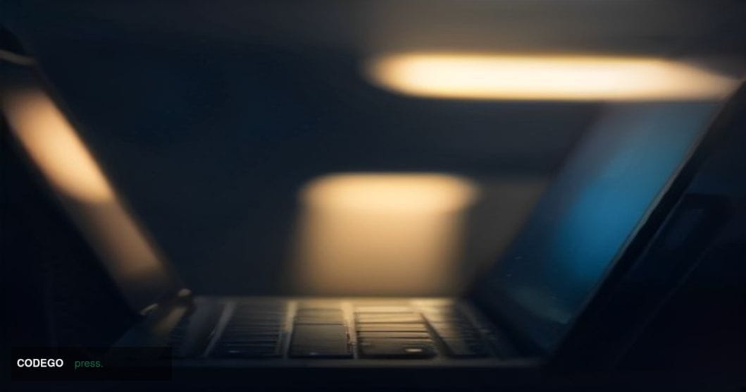 A cinematic editorial photograph shot in a dimly lit environment, depicting a close-up of a sleek laptop keyboard in sharp fo