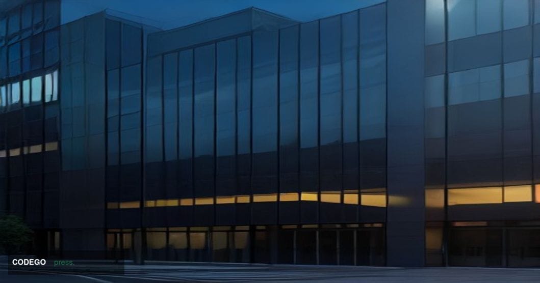 A sleek, modern corporate headquarters building photographed at dusk with warm amber interior lighting glowing through floor-