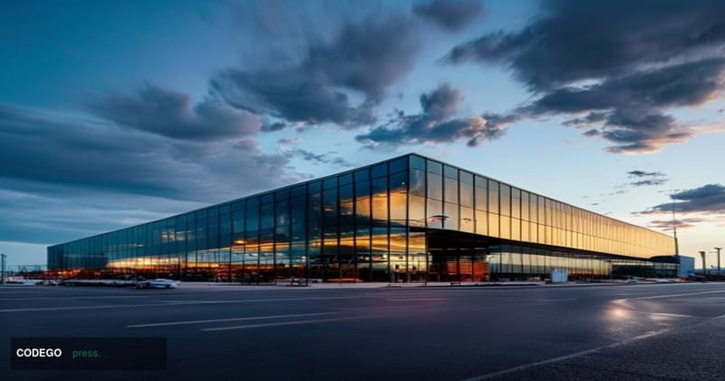 A cinematic editorial photograph showing Tesla's distinctive Gigafactory Shanghai exterior with its modern glass and steel ar