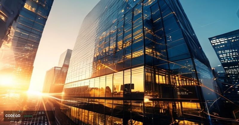A dramatic aerial photograph of a modern insurance company headquarters building in downtown financial district during golden
