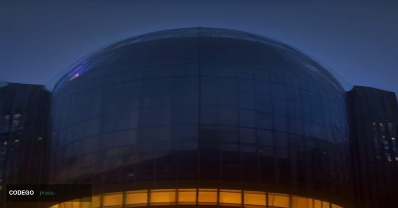 A cinematic editorial photograph taken from a low angle looking up at Amazon's iconic Seattle headquarters campus, the glass 