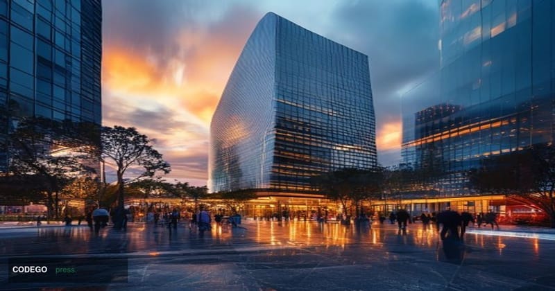 A dramatic wide-angle exterior shot of a modern Los Angeles financial district office tower at dusk, with warm amber sunset l