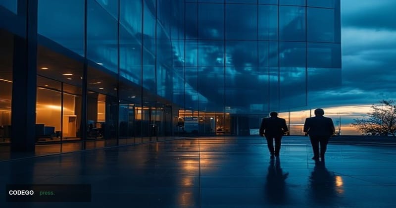 A cinematic editorial photograph of the BitMEX exchange logo displayed on a large dark glass office building facade at dusk, 