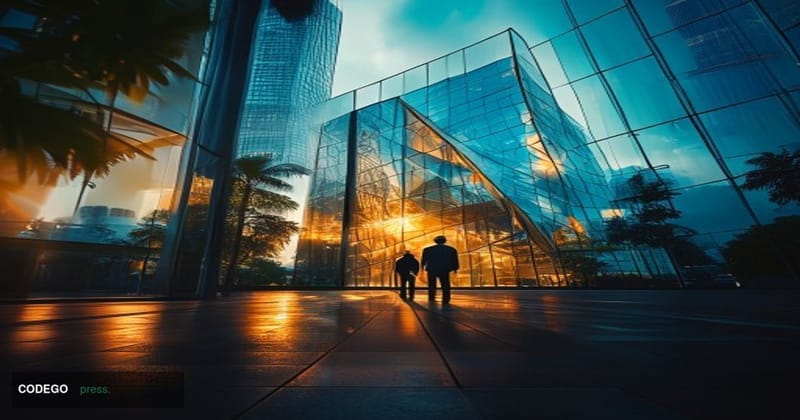 A cinematic editorial photograph shot at ground level looking up at a modern glass-and-steel technology campus building in Is